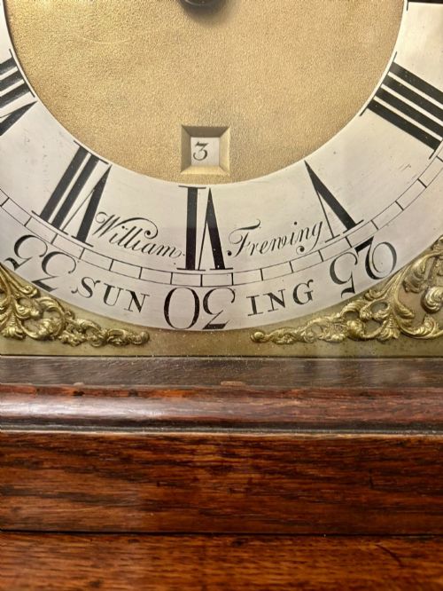 fig 3. A George III oak and burr oak longcase clock featuring a square brass dial, fretwork hood frieze, and a long waist door.