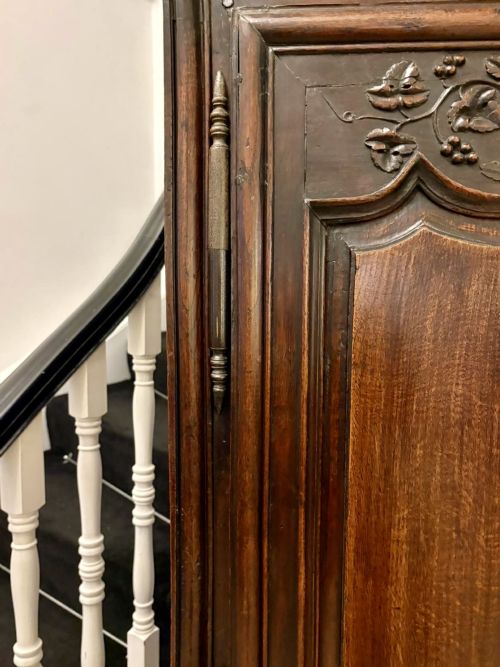 fig 5. A late 17th-century French Provincial dark oak armoire featuring two panelled doors with relief carvings, long steel hinges, and a moulded top cornice.
