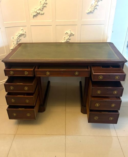A Victorian mahogany pedestal desk featuring a green leather inset writing surface, brass ring handles, and two drawer pedestals framing a central kneehole. View IX