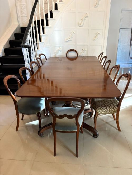 fig 3. A polished Regency mahogany dining table featuring a three-pillar pedestal base with splayed reeded legs ending in brass castors.