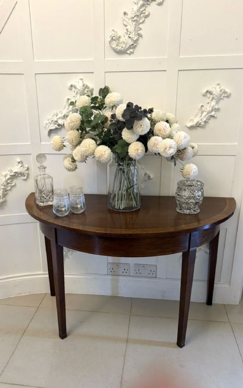 A pair of George III semi-circular mahogany console tables featuring crossbanded tops and square tapered legs. View III