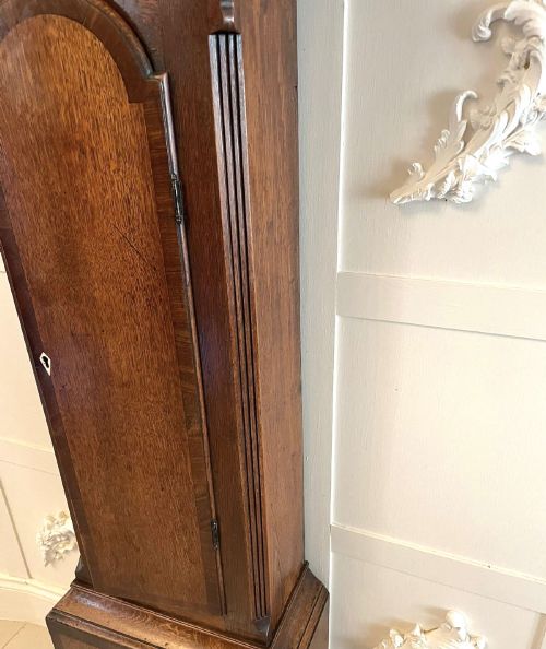 fig 1. A George III oak longcase clock featuring an etched brass dial with silvered chapter ring, inlaid wood motif pediment, and an arched trunk door.