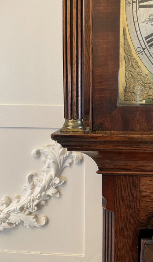 A George III oak longcase clock featuring an etched brass dial with silvered chapter ring, inlaid wood motif pediment, and an arched trunk door. View VII