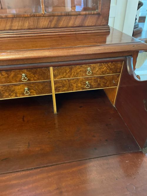 fig 1. An antique Regency mahogany secretaire bookcase featuring a top scroll pediment, glazed upper doors with astragal moulding, and a lower double cupboard.