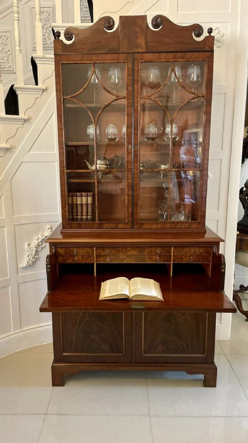 An antique Regency mahogany secretaire bookcase featuring a top scroll pediment, glazed upper doors with astragal moulding, and a lower double cupboard. View XI