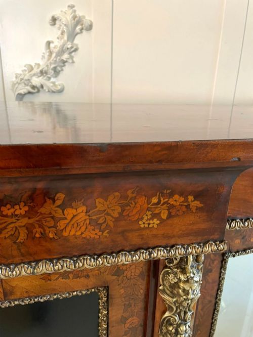 fig 6. A Victorian burr walnut breakfront credenza featuring brass mounts, a central floral marquetry panel, and mirrored side doors.