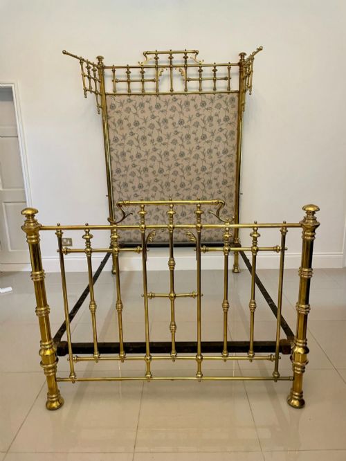 fig 1. An antique Victorian solid brass half tester double bed featuring turned posts, spindle balusters, cast decorative mounts, and an upholstered floral panel.