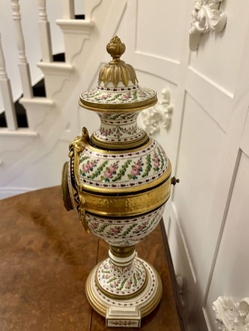 fig 2. A French hand-painted porcelain urn-shaped mantel clock featuring gold leaf accents, cobalt blue borders, and pink floral garlands on a gilded pedestal base.