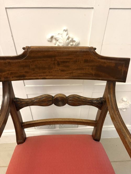 fig 4. A set of twelve Regency mahogany dining chairs featuring tablet top back rails, carved crossbars, and terracotta fabric upholstered seats, including two carvers with curved armrests.