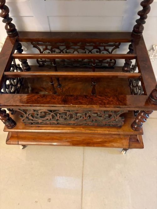 fig 4. A Victorian burr walnut Canterbury featuring a top surface with a pierced fretwork gallery, barley twist supports, divided slots, and a single drawer resting on porcelain castors.