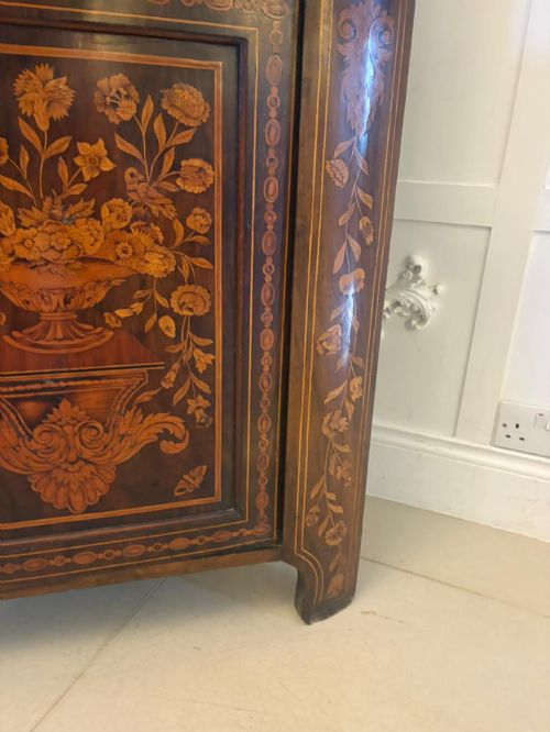 fig 1. A 19th-century two-tier Dutch marquetry corner cabinet featuring intricate floral inlays, an arched glazed top door, and a solid lower cupboard door.