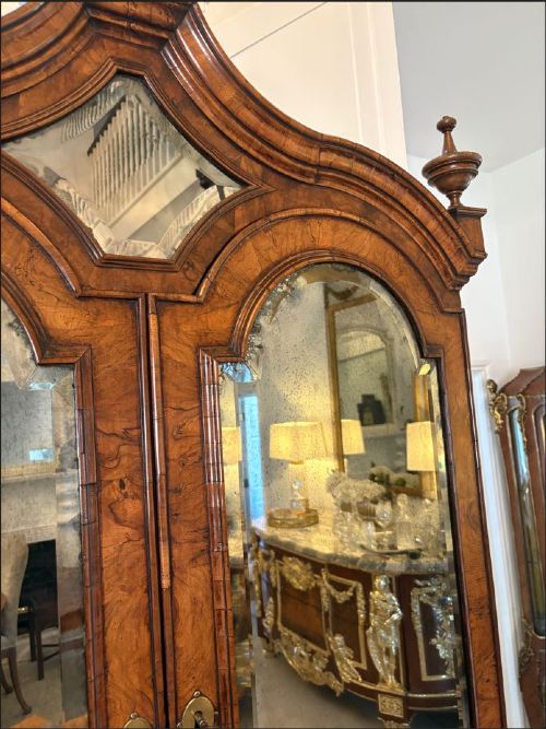 An antique Queen Anne burr walnut bureau bookcase featuring a double-domed cresting with urn finials, double mirrored doors, a sloping fall-front desk section, and a chest of drawers on bun feet. View XI