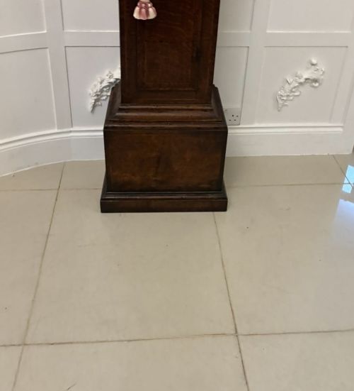 A George III oak longcase clock featuring an engraved brass dial face, a shaped trunk door, and a stepped pedestal base. View XIII