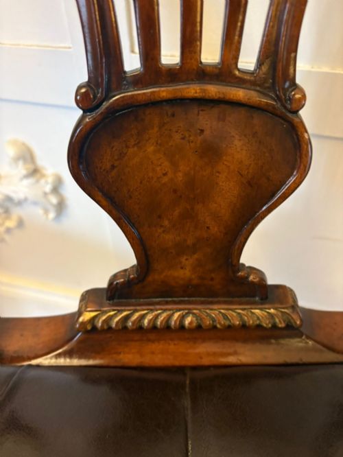 fig 1. Set of eight Edwardian carved walnut dining chairs featuring pierced backrests, gilded highlights, cabriole legs, and dark brown button-tufted leather seats.