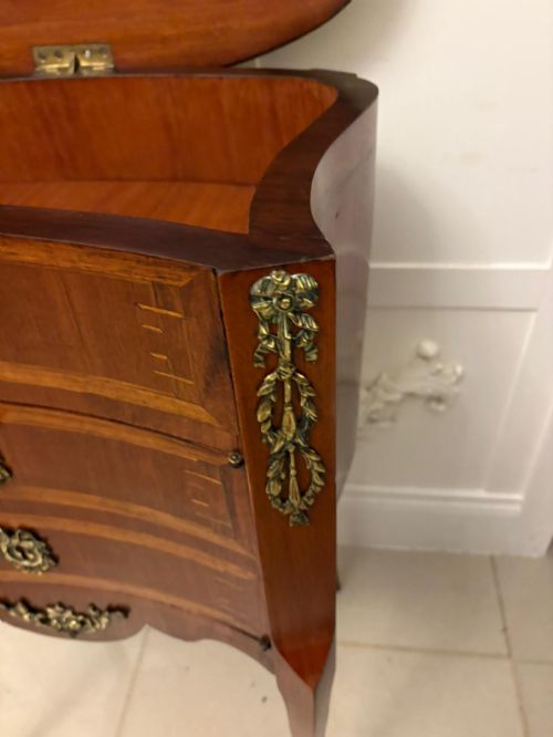 fig 2. An antique French Louis XV style wooden side cabinet featuring three marquetry drawers, brass rim, decorative corner mounts, and slender cabriole legs.