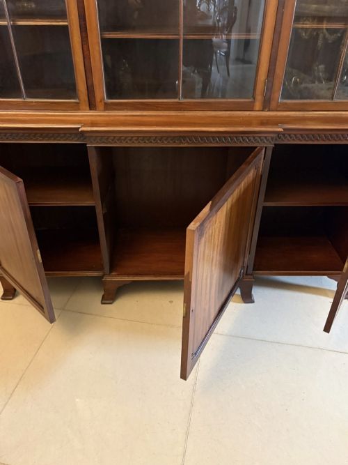 fig 3. An antique Edwardian mahogany breakfront bookcase featuring three glazed upper doors with astragal moulding above three solid wooden cabinet doors.