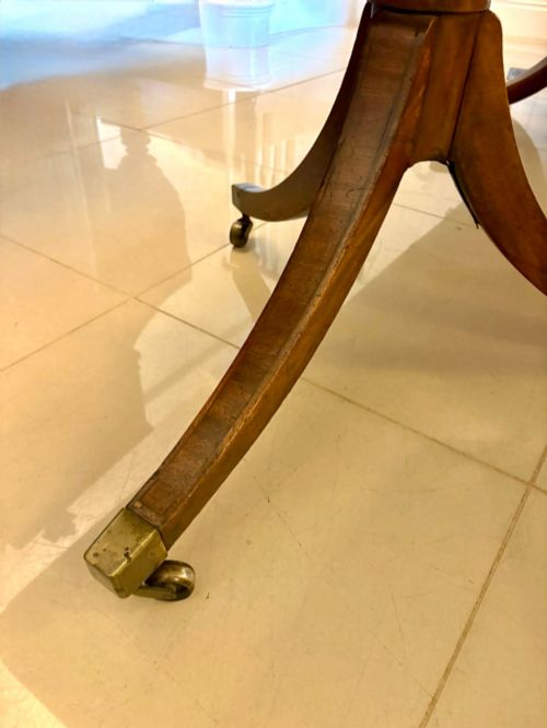 fig 2. A long Regency mahogany extending dining table supported by turned pedestal pillars with splayed legs and brass castors.
