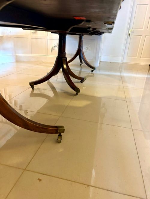 fig 3. A long Regency mahogany extending dining table supported by turned pedestal pillars with splayed legs and brass castors.
