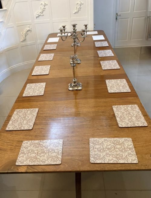 A long Regency mahogany extending dining table supported by turned pedestal pillars with splayed legs and brass castors. View XII