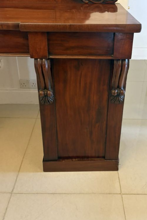 A Victorian mahogany pedestal sideboard featuring a raised backboard with carved scrollwork and two flanking pedestal cupboards. View VI