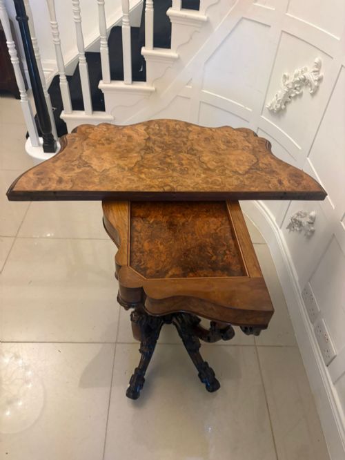 fig 1. A Victorian burr walnut card table featuring a serpentine-shaped fold-over top set upon a carved pedestal base with four scroll feet on castors.