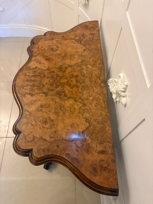fig 2. A Victorian burr walnut card table featuring a serpentine-shaped fold-over top set upon a carved pedestal base with four scroll feet on castors.