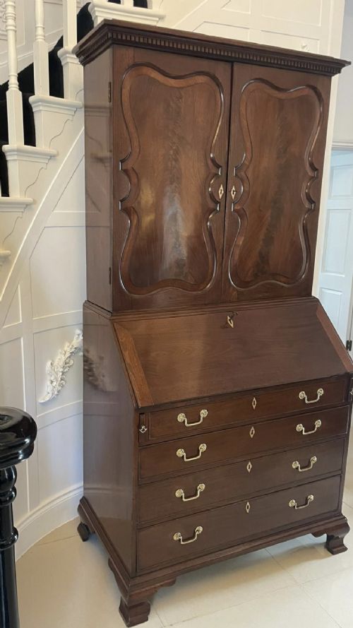 A George II figured mahogany bureau bookcase featuring shaped panel upper doors above a slant-front writing slope and four graduated drawers on bracket feet. View IX