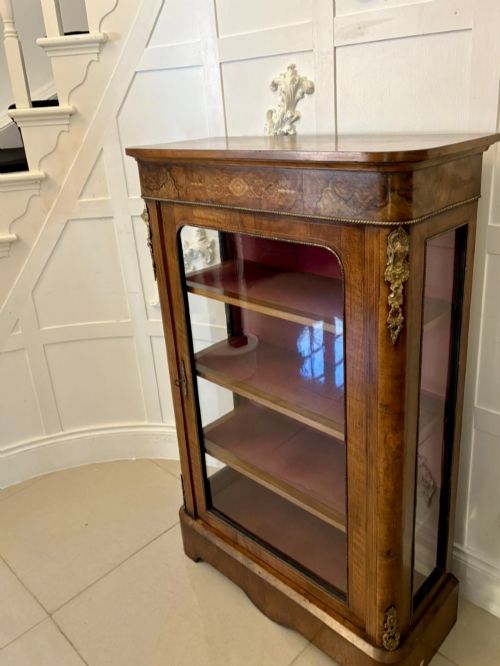 fig 1. A Victorian burr walnut pier cabinet featuring a single glazed door, floral marquetry along the frieze, and gilt ormolu corner mounts.