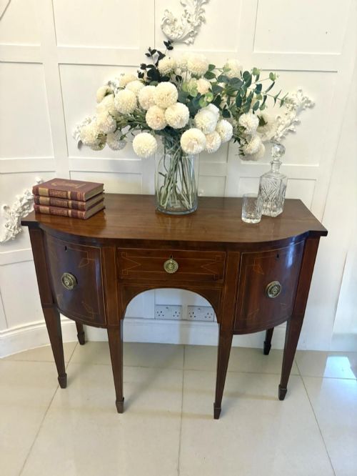 fig 1. A George III mahogany sideboard featuring geometric boxwood stringing inlay, brass rosette handles, a central arch drawer, and square tapered legs.