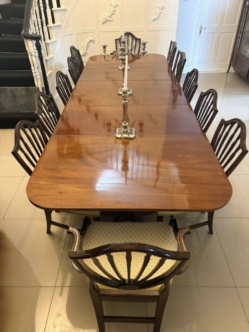 fig 1. A large Georgian extending dining table crafted from polished figured mahogany with a three-pillar tripod pedestal base and brass castors.