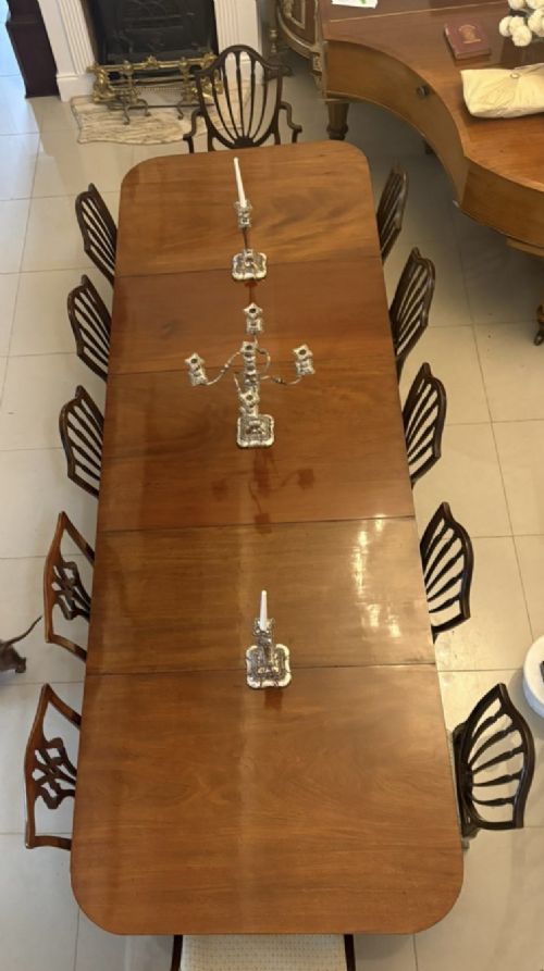 fig 2. A large Georgian extending dining table crafted from polished figured mahogany with a three-pillar tripod pedestal base and brass castors.