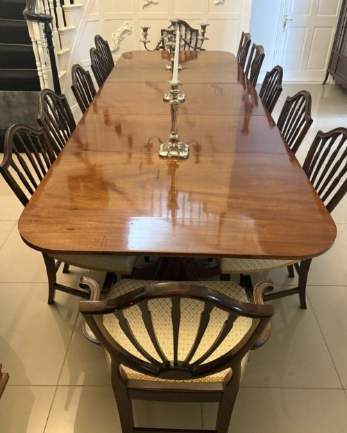 fig 4. A large Georgian extending dining table crafted from polished figured mahogany with a three-pillar tripod pedestal base and brass castors.