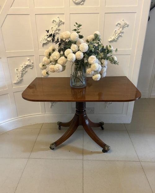 fig 5. A large Georgian extending dining table crafted from polished figured mahogany with a three-pillar tripod pedestal base and brass castors.