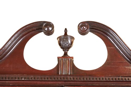 fig 1. A Victorian mahogany breakfront display cabinet with astragal glazed doors, open side shelves, and a swan-neck pediment topped with an urn finial.