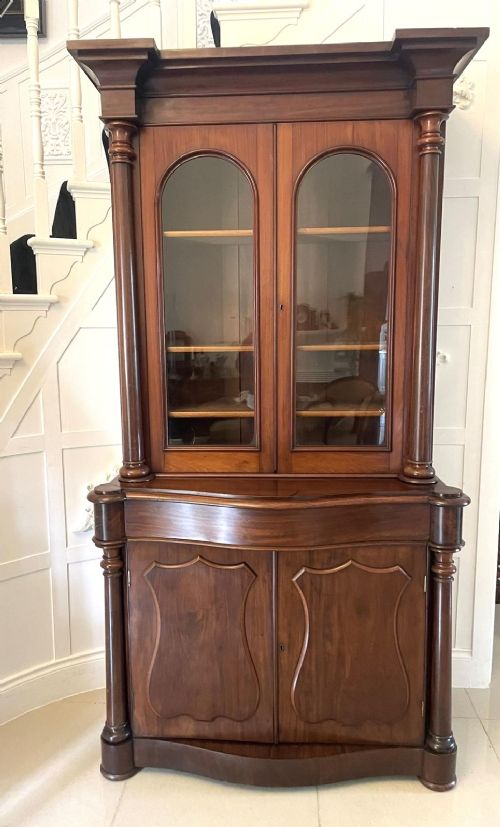 A Victorian mahogany glazed bookcase featuring two upper arched glass doors flanked by turned columns above a curved two-door cupboard base. View II