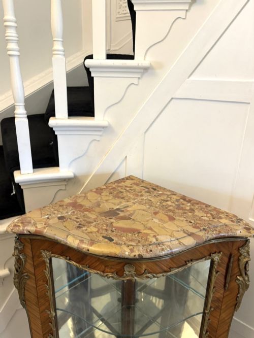 fig 4. An antique French serpentine corner display cabinet crafted from kingwood with a marble top, curved glass door, internal glass shelves, and gilded ormolu mounts.
