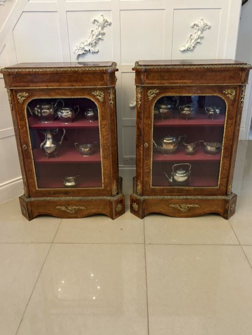 fig 1. A pair of Victorian burr walnut pier cabinets featuring glazed front doors, velvet-lined interior shelves, and ornate gilt metal mounts.