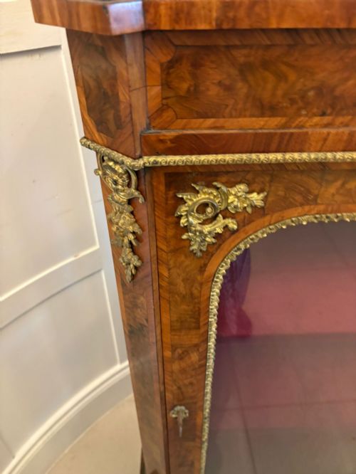 fig 4. A pair of Victorian burr walnut pier cabinets featuring glazed front doors, velvet-lined interior shelves, and ornate gilt metal mounts.