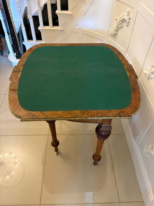 fig 3. A Victorian burr walnut fold-over card table featuring geometric inlay, turned support legs on castors, and decorative brass edge moulding.