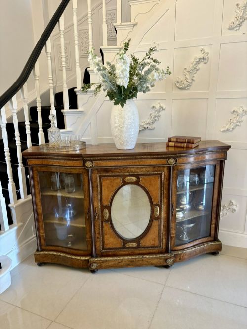 fig 2. A Victorian burr walnut credenza featuring a central oval mirrored door flanked by curved bow-front glass doors and gilt ormolu mounts.