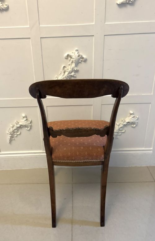 A set of four antique Regency rosewood dining chairs featuring carved scroll top rails and pattern-upholstered seats on turned front legs. View V