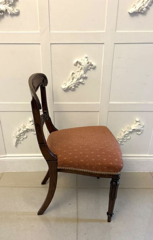 A set of four antique Regency rosewood dining chairs featuring carved scroll top rails and pattern-upholstered seats on turned front legs. View VI