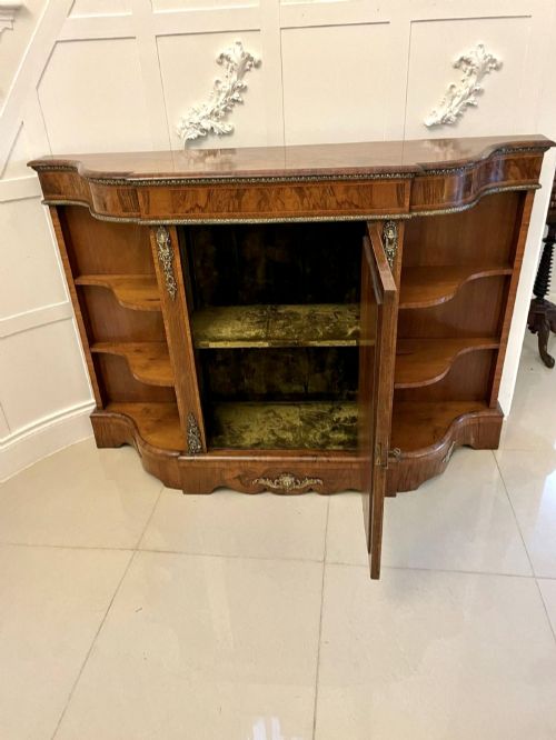 fig 3. A Victorian burr walnut credenza featuring a central glass door, open serpentine display shelves, and detailed brass ormolu mounts.