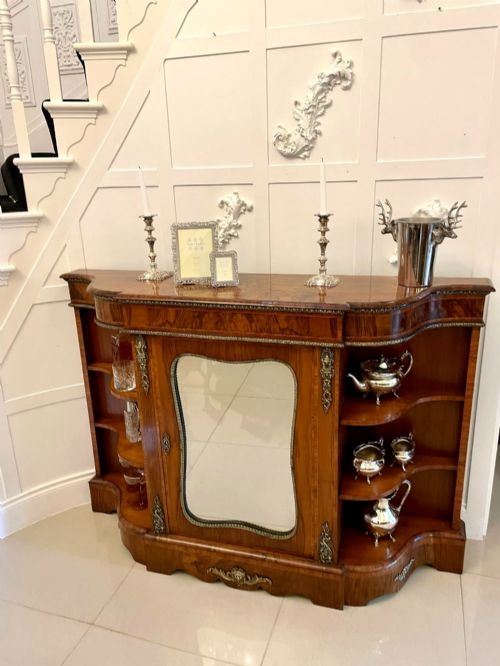 fig 4. A Victorian burr walnut credenza featuring a central glass door, open serpentine display shelves, and detailed brass ormolu mounts.