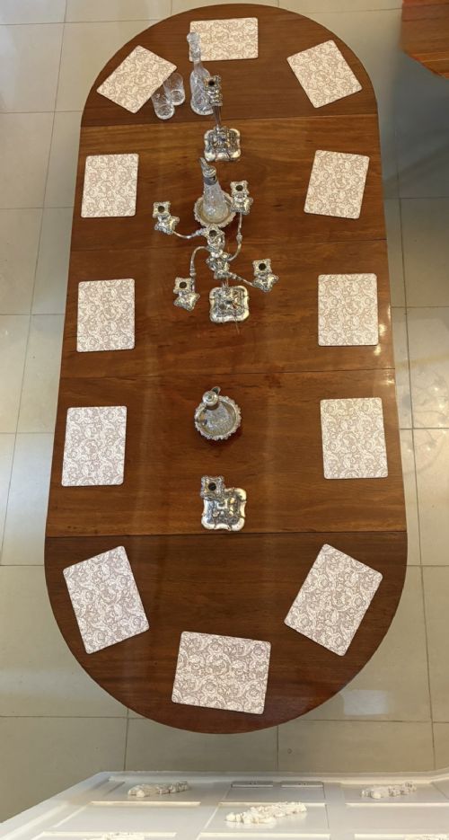 A large extended Georgian mahogany dining table featuring curved D-shaped ends, polished figure top, and slender legs with pad feet. View XI