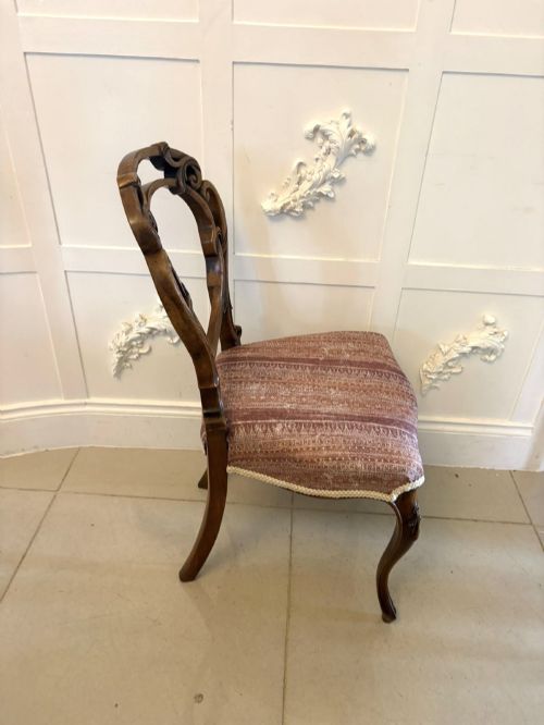 fig 2. A set of four Victorian walnut balloon back dining chairs featuring carved openwork backrests, cabriole front legs, and patterned rose-coloured upholstered seats.