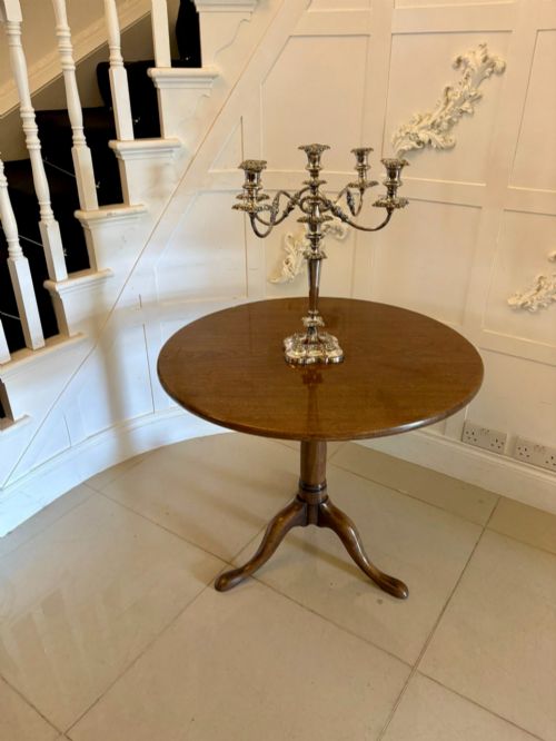 fig 1. An 18th-century Georgian circular mahogany tilt-top table shown with its surface tilted vertically on a turned column with three cabriole legs.