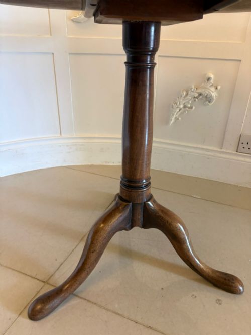 fig 2. An 18th-century Georgian circular mahogany tilt-top table shown with its surface tilted vertically on a turned column with three cabriole legs.