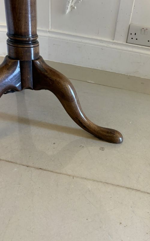 fig 3. An 18th-century Georgian circular mahogany tilt-top table shown with its surface tilted vertically on a turned column with three cabriole legs.