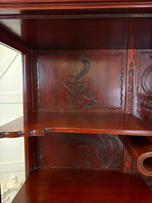 fig 3. A carved reddish-brown hardwood display cabinet featuring a pagoda cresting, glass door, asymmetrical interior shelves, lower drawers, and cabriole legs.